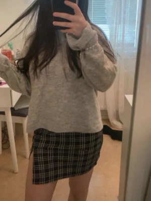 Svartvit rutig kortkjol med slits - Trendig svartvit rutig kortkjol med slits på sidan. Kjolen har en tight passform och klassiskt rutmönster. 