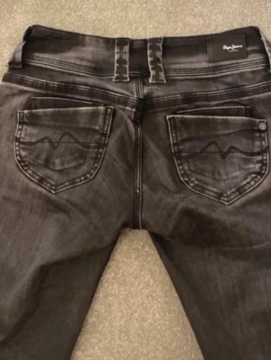 Svarta jeans från Replay - Säljer ett par svarta jeans från Replay med snygga detaljer på bakfickorna och dubbla bälteshällor. Jeansen har en smal passform och klassisk femficksdesign. Materialet är stretchigt denim som sitter skönt hela dagen.