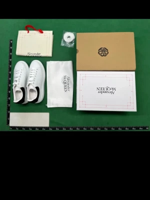 Alexander McQueen vita sneakers - Stilrena vita sneakers från Alexander McQueen med svart detalj på hälen och tjock sula. Klassisk låg modell med vita skosnören och perforerade sidor. Kommer med originalkartong, dustbag och extra skosnören.