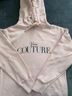 Ljusrosa Viva Couture hoodie - Säljer en ljusrosa hoodie från Viva Couture med tryckt logga framtill. Hoodien har huva och långa ärmar. Perfekt för en avslappnad och trendig look. Mjuk bomullsblandning som känns skön och mjuk mot huden.