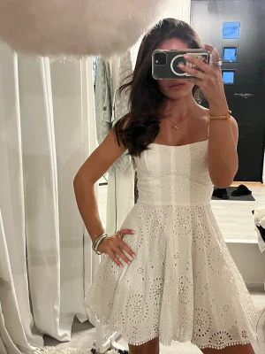 Söt Vit volang klänning med broderi - Säljer en superfin vit klänning med tunna axelband och vackra broderade detaljer. Klänningen har en lätt utsvängd kjol och sitter snyggt i midjan. Perfekt för sommarens alla tillfällen! 💫 dragkedja på sidan 