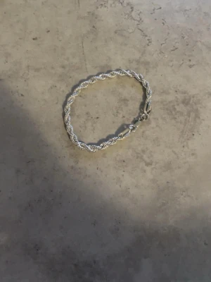 Silvrigt tvinnat armband - Snyggt armband i silverfärgad metall med tvinnad kedja och karbinlås. Armbandet har en stilren och modern look som passar till många olika stilar. Perfekt accessoar för dig som gillar minimalistiska smycken. Den är aldrig några få gånger och priset är billigt eftersom använder den aldrig så vill att den säljs snabbt