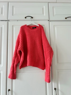 Oversized rosa stickad tröja Gina Tricot - Säljer en oversized stickad tröja i starkt rosa från Gina Tricot. Tröjan har grov ribbstickning, rund halsringning och extra långa ärmar med snygga detaljer. Perfekt för dig som gillar en chill och trendig look.