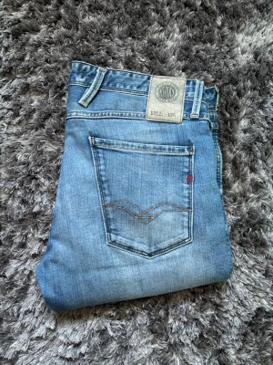 Replay Jeans - Blå Replay anbass jeans 32/32 Längd 106cm Midja 43cm Slimfit Jeansen är stretchiga och i bra skick, enda defekten är förtunningen i skrevet (se sista 2 bilderna).