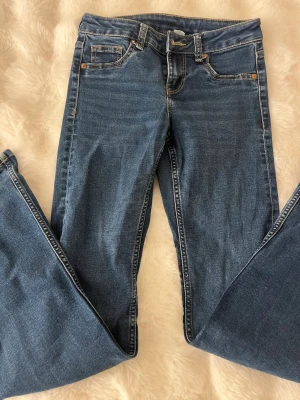 Mörkblåa bootcut jeans - Säljer ett par mörkblåa bootcut jeans i storlek 34. Finns små slitningar längst ner på jeansen.