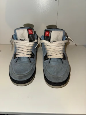 Jordan 4 University Blue sneakers - Säljer ett par Jordan 4 University Blue sneakers i blå mocka med vita och svarta detaljer. Skorna har vita snören, meshpaneler på sidorna och en tydlig '23'-detalj på plösen. Klassisk siluett och bekväm sula.