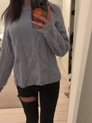 Ljusblå ribbstickad tröja - Mysig ljusblå stickad tröja med ribbad struktur och avslappnad passform. Tröjan har långa ärmar och rund halsringning, perfekt för lager på lager under kyliga dagar. Enkel och stilren design utan synligt märke.