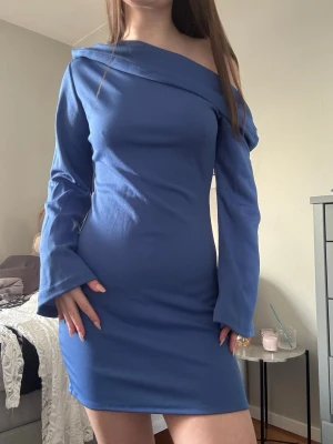 Blå offshoulder kort klänning - Säljer en blå, figurnära kort klänning med offshoulder-design och långa ärmar💙