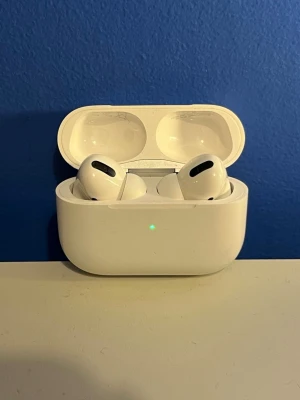 Apple AirPods Pro  - Säljer ett par vita Apple AirPods Pro med laddningsetui. De har en stilren och kompakt design, silikonproppar för bra passform och brusreducering. Perfekta för musik, samtal och träning. Kopplas enkelt till din iPhone eller annan Apple-enhet.