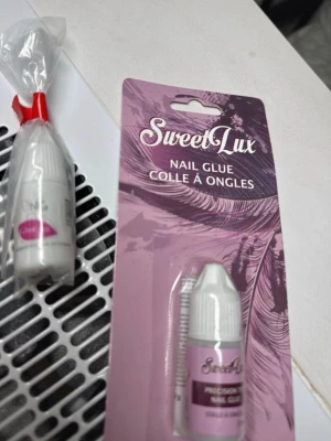 SweetLux nagellim 2 ml från Nagelgiganten/100kr - Nagellim från SweetLux/Nagelgiganten  i en liten vit plastflaska med lila etikett. Förpackningen innehåller 2 ml lim och har en precisionstopp för enkel applicering av lösnaglar eller dekorationer. Perfekt för dig som vill fixa naglarna snabbt och smidigt hemma.