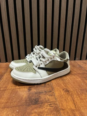 Nike Air Jordan 1 Low Travis Scott golf - Nike Air Jordan 1 Low sneakers i olivgrönt och beige med svart swoosh på sidan. Skorna har vita snören, perforerad tåbox och en slitstark gummisula med klassiskt mönster. Skorna är så gott som ny och har inga slitningar på sulan för golfspel. Medföljer även svarta och gröna snören!
