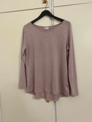 Ljusrosa långärmad tröja från Vila - En enkel och mjuk ljusrosa långärmad tröja från Vila. Tröjan har rund halsringning och rak passform med något längre bakstycke. Perfekt att matcha med jeans eller kjol för en avslappnad look.