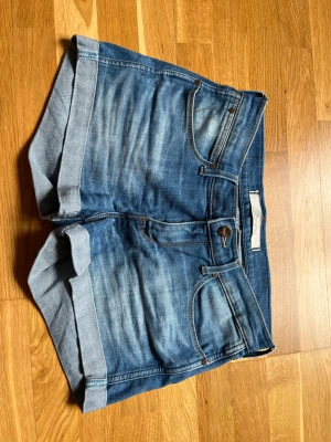 Wrangler jeansshorts - Jeansshorts från Wrangler strl 26. Midjemått tvärsöver ca 33,5 enligt bild. Low/mid rise. 