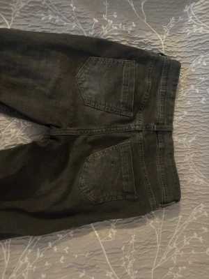 Mörkgråa bootcut jeans med  fickor - Säljer ett par mörkgrå jeans med klassisk femficksdesign dom är bootcut och mid waist typ. Jeansen har bälteshällor, knappgylf och två bakfickor med enkel söm. Perfekta för en avslappnad och stilren look.Har använt dom nåra få gånger och dom är i bra skick.Köpte ifrån H&M för runt 300kr för ett tag sen.Tror inte dom finns kvar för att köpa.