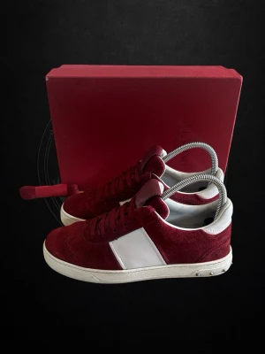 Vinröda Flycrews dam. - Snygga vinröda sneakers i mocka från Stiksen med vit läderdetalj på sidan och vit sula. Skorna har klassisk låg profil och stilrena linjer, perfekta för dig som gillar en clean look. Levereras med matchande röd skokartong och skoborste.