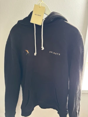 Svart hoodie från Axel Arigato - Svart hoodie från Axel Arigato i grymt bra skicka! En fin och stilren design, köpt för 2100 kr från deras hemsida. Jag säljer för 900 prutat och klart!  Kartong och påse medföljer