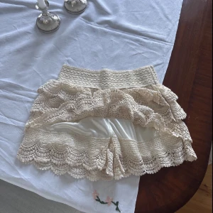 Beige spetsshorts med volanger - Superfina beige virkade shorts med flera lager volanger. De har en elastisk midja och är perfekta för varma dagar.