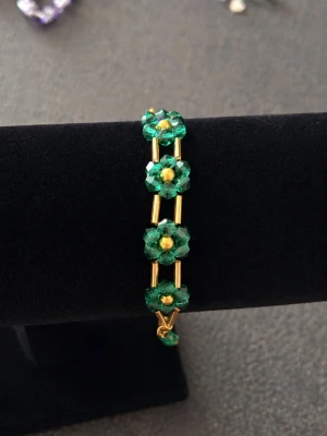 Grönt och guldigt pärlarmband med blommor -  armband med gröna pärlor formade som små blommor och guldfärgade detaljer. 
