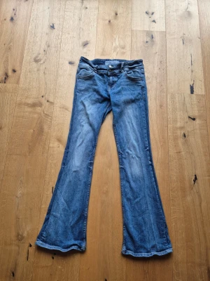 Blå bootcut jeans - Säljer ett par blå bootcut jeans med låg midja. De har inga slitningar utöver att de är rynkliga men det går lätt att fixa med strykjärn!
