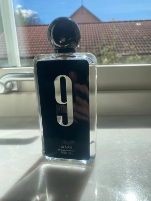 Afnan 9PM Eau de Parfum 100ml - Afnan 9PM är en parfym i en stilren, rektangulär glasflaska med svart etikett och stor vit siffra 9 på framsidan. Flaskan har en rund, svart kork och rymmer 100 ml. Doften är unisex och passar dig som gillar moderna och eleganta parfymer.