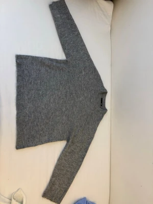 Grå stickad tröja från Lager 157 S men passar som M - Mysig grå stickad tröja från Lager 157 med rund halsringning och ribbade muddar vid ärmslut och nederkant. Perfekt för lager-på-lager och enkel att matcha med jeans eller kjol. Klassisk och stilren design i mjukt material.