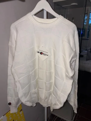 Vit stickad tröja från McLaren - Säljer en helt ny och oanvänd vit stickad tröja från McLaren of Scotland med diskret rutmönster och ribbade muddar vid hals, ärmslut och nederkant. Klassisk rund halsringning och en liten logodetalj på ärmen. Perfekt för dig som gillar stilrena plagg. Nypris 600kr, säljer den för 350kr.