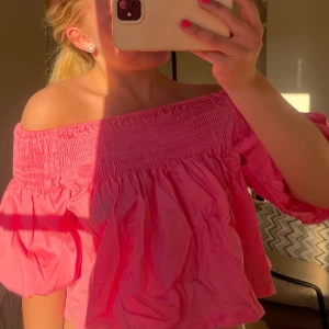Rosa offshoulder topp🩵 - Söt rosa offshoulder topp med smockad överdel och puffiga korta ärmar. Toppen har en croppad passform och är perfekt för varma dagar. Tillverkad i ett lätt och luftigt material som känns skönt mot huden.