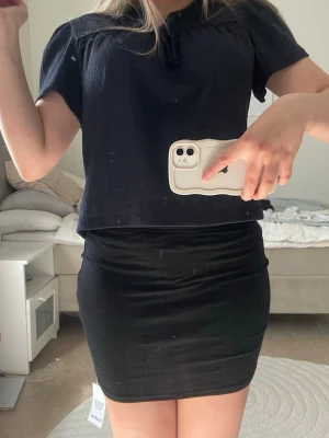Svart tight kortkjol - Enkel och stilren svart kortkjol med tight passform. Kjolen är rak i modellen och passar perfekt till både toppar och t-shirts. Materialet känns mjukt och följsamt mot kroppen. Perfekt för dig som gillar minimalistisk och klassisk stil.