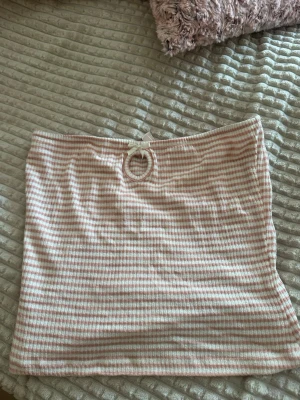 Randig bandeau tubtopp med rosett - Söt bandeau tubtopp med ljusrosa och vita ränder. Toppen har en liten rosett framtill och är axelbandslös, perfekt för varma dagar. Mjuk och stretchig känsla.