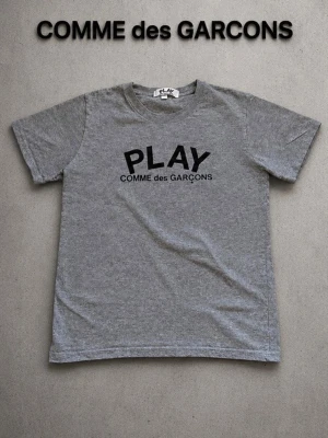 CDG T-shirt  - Stilren CDG t shirt köpt secondhand. Säljer då den är för liten för mig, tröjan är i mycket bra skick hör av er vid minsta fråga. Det är storlek M men sitter som S W priset ar ej hugget i sten • Märke: COMME des GARÇONS • Färg: Grå • Storlek: M (sitter som S) • Skick: Mycket bra Så mycket jag kan se är den äkta
