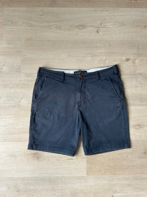 Blåa Hollister Chinosshorts Shorts Storlek W34 - Mycket fina Hollister shorts i blå färg | Jeansen är i mycket bra skick och sparsamt använda. |  Äkta som allt annat jag säljer! ✅ |  Storlek: W34 | Skick: Mycket Bra Skick - Har en väldigt liten slitning (SE SISTA BILD) | Färg: Blå | Märke: Hollister| Modell: Shorts |   Hör gärna av dig vid frågor så svarar jag så fort jag kan! 😁 |  (SKU - 180)