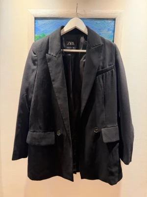 Svart kavaj från Zara XS - Stilren svart kavaj från Zara i storlek XS. Fodrad med 100% återvunnen polyester. Perfekt för en trendig och snygg look.