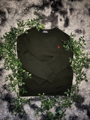 Polo Ralph Lauren sweatshirt svart  - Svart sweatshirt från Polo Ralph Lauren med röd broderad logga på bröstet. Enkel och stilren modell som passar till allt. Tröjan är i fint skick och väldigt bekväm att använda till vardag. • Färg: Svart • Märke: Polo Ralph Lauren • Broderad logga framtill • Mjuk och skön passform • Passar både casual och clean outfit Skriv gärna vid frågor eller intresse 😊