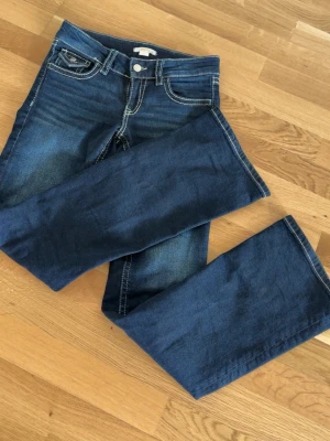 Mörkblå bootcut jeans Gina Tricot - Snygga mörkblå bootcut jeans från Gina Tricot med kontrastsömmar och klassisk femficksmodell. Jeansen har en normalhög midja och är tillverkade i ett mjukt denimtyg som sitter skönt. Perfekta till sneakers eller boots.