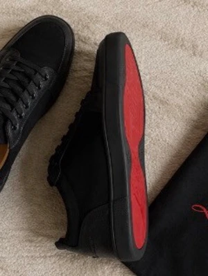 Christian Louboutin Retero logo leather sneakers - Snygga svarta sneakers från Christian Louboutin med klassisk röd sula. Skorna har en mix av läder och mocka, svarta skosnören och diskreta detaljer. Perfekta för dig som vill ha en stilren men ändå unik look.