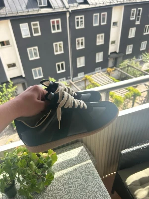 Svarta Maison Margiela sneakers - Snygga svarta sneakers från Maison Margiela med vita skosnören, skorna är i jätte bra skick och perfekta till sommaren. Hör av er vid frågor och funderingar 
