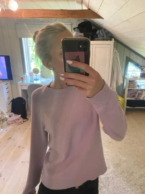 Ljusrosa stickad tröja - Säljer en enkel och stilren ljusrosa stickad tröja med rund halsringning och långa ärmar. Tröjan har en rak passform och ribbstickade muddar vid ärmslut och ned kant.