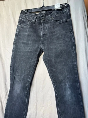 Grå jeans från Jack & Jones - Snygga grå jeans från Jack & Jones med klassisk femficksmodell och raka ben. Jeansen har en tvättad look och är tillverkade i mjuk bomullsdenim med lite stretch för extra komfort. Perfekta till en avslappnad stil.