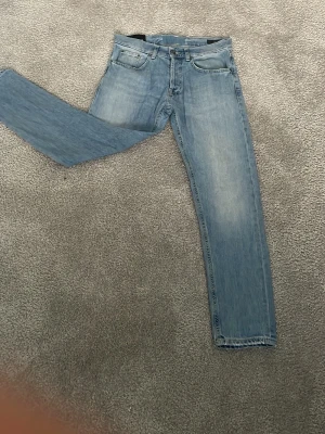 Ljusblå raka jeans från DonDup  - Säljer ett par ljusblå jeans från DonDup med raka ben och klassisk femficksdesign. Jeansen har subtila slitningar för en avslappnad look. Tillverkade i bomullsdenim.