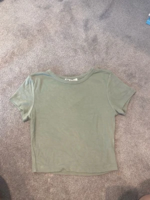 Grön croppad topp från Zara - Snygg ljusgrön croppad topp från Zara med korta ärmar och rund halsringning. Tillverkad i mjuk bomull som känns skön mot huden. Perfekt att matcha med jeans eller kjol för en chill look.