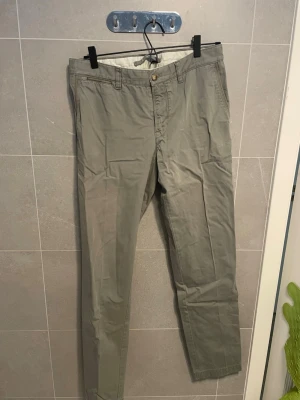 Olivgröna chinos - Ser lite skrinkliga ut men det är for de har legat i garderoben i typ ett år. Har bara använt dem en gång så de är i princip helt nya. Snygga olivgröna chinos med raka ben och klassisk passform. Byxorna har framfickor, två bakfickor med knappdetalj och bälteshällor. Tillverkade i ett mjukt bomullstyg som ger en avslappnad look. 