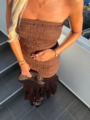 Chokladbrun broderad bandue långklänning med volanger nedtill - Chokladbrun broderad bandue långklänning i spets med massvis lager av volanger nedtill. Supersnygg & elegant med massvis av vackra broderade mönster 🤎Köpt på Prettylittlething, PLT för 1500kr. Lappar bortklippta men har kvitto som kan garantera äktheten. Använd en gång. 🤎