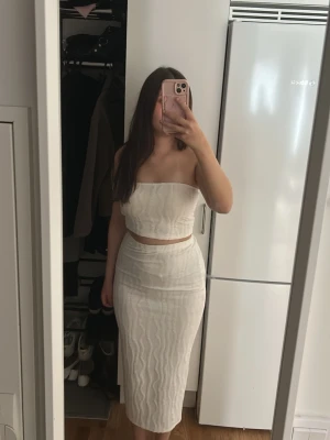 Vitt ribbat tvådelat set - Jag säljer ett vitt tvådelat set från Shein med en bandeau-topp och en figurnära kjol i ribbat material. Kjolen sitter nära till midjan och framhäver en fin form. Materialet är skönt och lite genomskinligt, men inte för mycket. Jag har använt det tidigare men inte längre, därför säljer jag det nu.