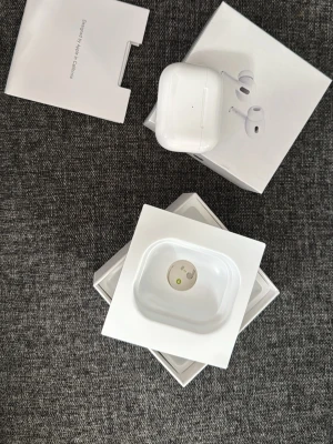 Apple AirPods Pro 2 trådlösa hörlurar - Säljer ett par vita Apple AirPods Pro 2 med laddningsetui. De är trådlösa in-ear hörlurar i snygg och kompakt design, tillverkade i plast. Perfekta för musik, samtal och träning. Originalförpackning och tillbehör medföljer. Helt nya och oanvända 