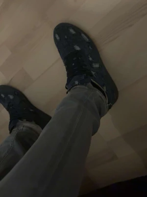 Maison margiela - Säljer ett par mörkblå sneakers i denim med slitna detaljer och mörkblåsskosnören.