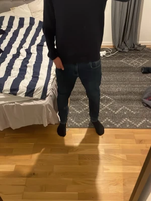 Mörkblå slim fit jeans - Säljer ett par mörkblå slim fit jeans med klassisk femficksdesign och lätt slitna detaljer. Jeansen har smal passform och normal midja, perfekta för en trendig och avslappnad look. Materialet är stretchigt för extra komfort. storlek 170, mycket bra skick