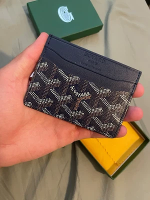 Korthållare - Exklusiv korthållare i blått läder med ikoniskt mönster i vitt och brunt. Smidig och stilren design med flera kortfack. Perfekt accessoar för dig som vill ha något unikt och lyxigt i fickan.