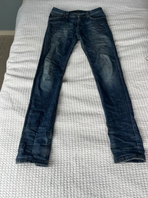 Mörkblå slim fit jeans - Snygga mörkblå slim fit jeans med lätt slitna detaljer och klassisk femficksmodell. Jeansen har normal midja och smala ben, perfekta till en avslappnad stil. Materialet är denim i bomull med lite stretch för extra komfort.
