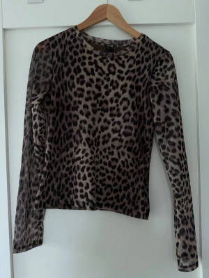 Leopardmönstrad mesh topp - Snygg långärmad topp i mesh med leopardmönster. Tunn och genomskinlig, perfekt att styla lager på lager. Rund halsringning och figurnära passform. Ger en edgy vibe till din outfit.
