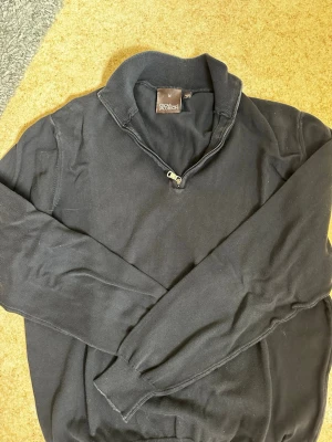 Mörkblå halvzip-tröja Oscar Jacobson - Mörkblå  långärmad tröja från Oscar Jacobson med halvzip och ståkrage. Tröjan har ribbade muddar vid ärmslut och nederkant. Perfekt för en stilren och avslappnad look. Säljs för 200kr. Kontakta mig om du har frågor eller vi lägga bud.